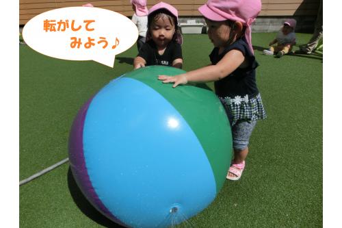 園庭に出ると<span style='color:#ff007f;'>大きなボール</span>が！<br><br>ボールが大好きな子ども達は<br>早速<span style='color:#ff7f00;'>コロコロ転がして</span>いると…<br>