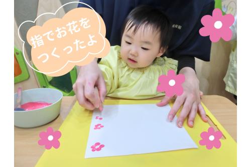 次は、<span style='color:#ff60af;'>お花をつくりました</span>♪<br><br>先生と一緒に<span style='color:#ff4c4c;'>指スタンプ</span>!<br>絵の具が手に着くのが苦手な子は<br><span style='color:#4ca5ff;'>スポンジスタンプ</span>に挑戦しました!<br>