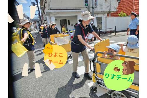 次は<span style='color:#ff7a7a;'>実際</span>に<span style='color:#00ff7f;'>公園</span>まで行くところを<br>見てもらいました！<br><br><span style='color:#ff00ff;'>うさぎチーム（2歳児）</span>は<span style='color:#bcff7a;'>先生と手をつないで</span>！<br><span style='color:#ffbc7a;'>りすチーム（1歳児）</span>と<span style='color:#7aff7a;'>ひよこチーム（0歳児）</span>は<br><span style='color:#7abcff;'>カートに乗って</span>行きます<span style='color:#ff00ff;'>♪</span><br><br><span style='color:#bc7aff;'>監視員</span>の保育者がしっかりと<br><span style='color:#7affbc;'>周囲の確認</span>を行い、<br>子どもたちが<span style='color:#ffbc7a;'>安全</span>に<span style='color:#ff5b5b;'>公園</span>まで<br>行くことができるようにしています<span style='color:#ff0000;'>！！</span>