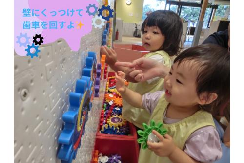 次のコーナーでは<span style='color:#ff007f;'>壁に歯車をつける</span>パズルのようなおもちゃが。<br><br>初めて見るおもちゃに<span style='color:#0582ff;'>少し戸惑って</span>いましたが<br>先生が実際に楽しんでいると真似をしてつけていました。<br><br>くるくるまわると<span style='color:#007fff;'>「できたー！」</span>と<br>達成感を感じる様子も見られました<span style='color:#ffff00;'>★</span>